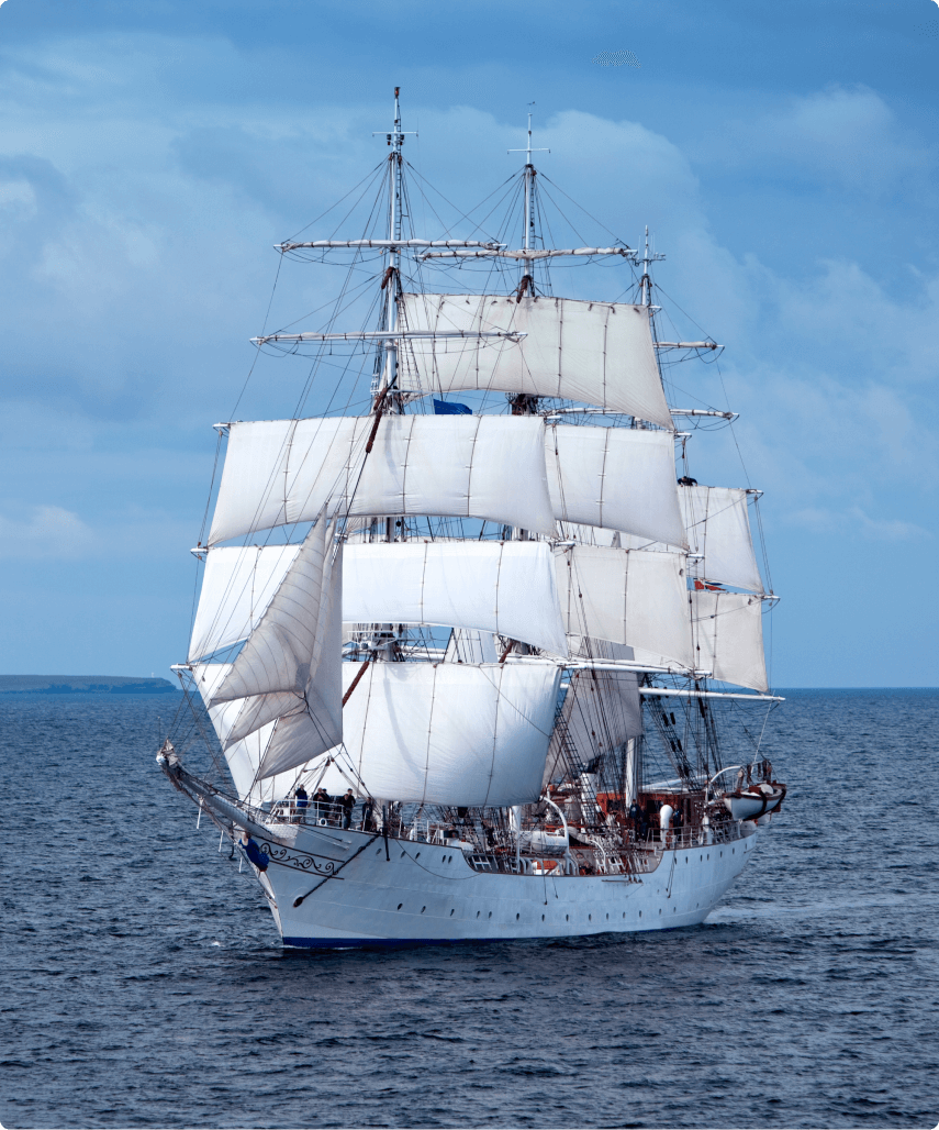 White sailboat with sails billowing in the wind.
