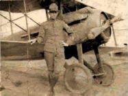 A man standing next to an airplane in the dirt.