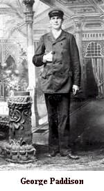A man in a suit standing next to a pillar.