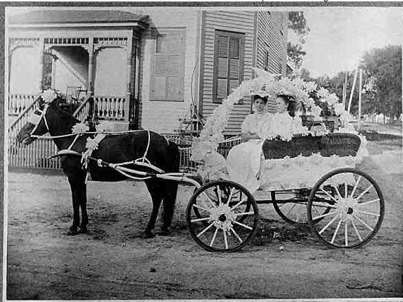 A horse drawn carriage with two women in it.