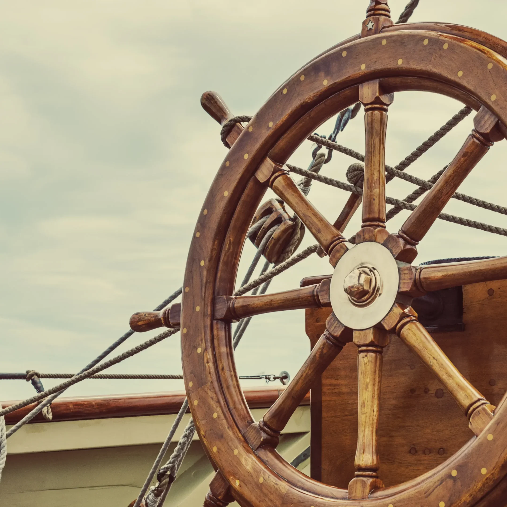 A large wooden wheel on the side of a boat.
